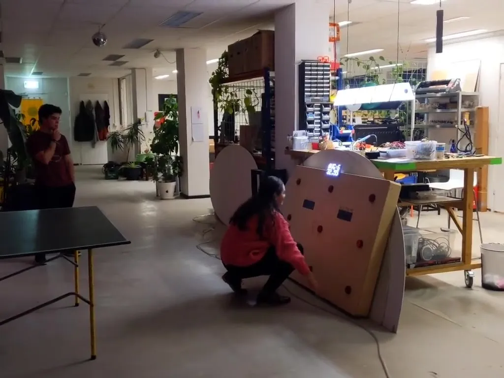 A person crouching to hit a lit target on the reaction panel in the studio